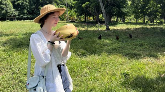 Student Djuana Nagasaki standing in an open field with a coconut in Cuba